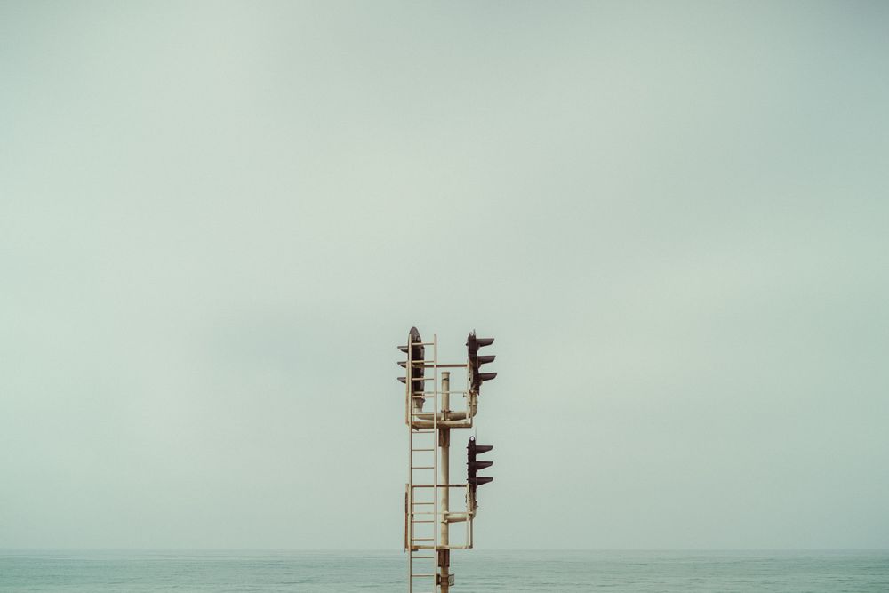 A series of cell phone towers stand against a misty sky, creating a minimalist industrial landscape.