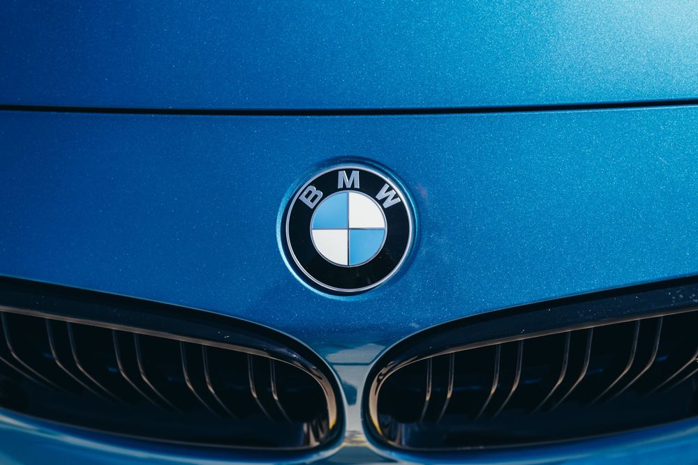 Close-up detail shots of a BMW car's exterior showing the iconic grille and hood design in metallic blue finish.