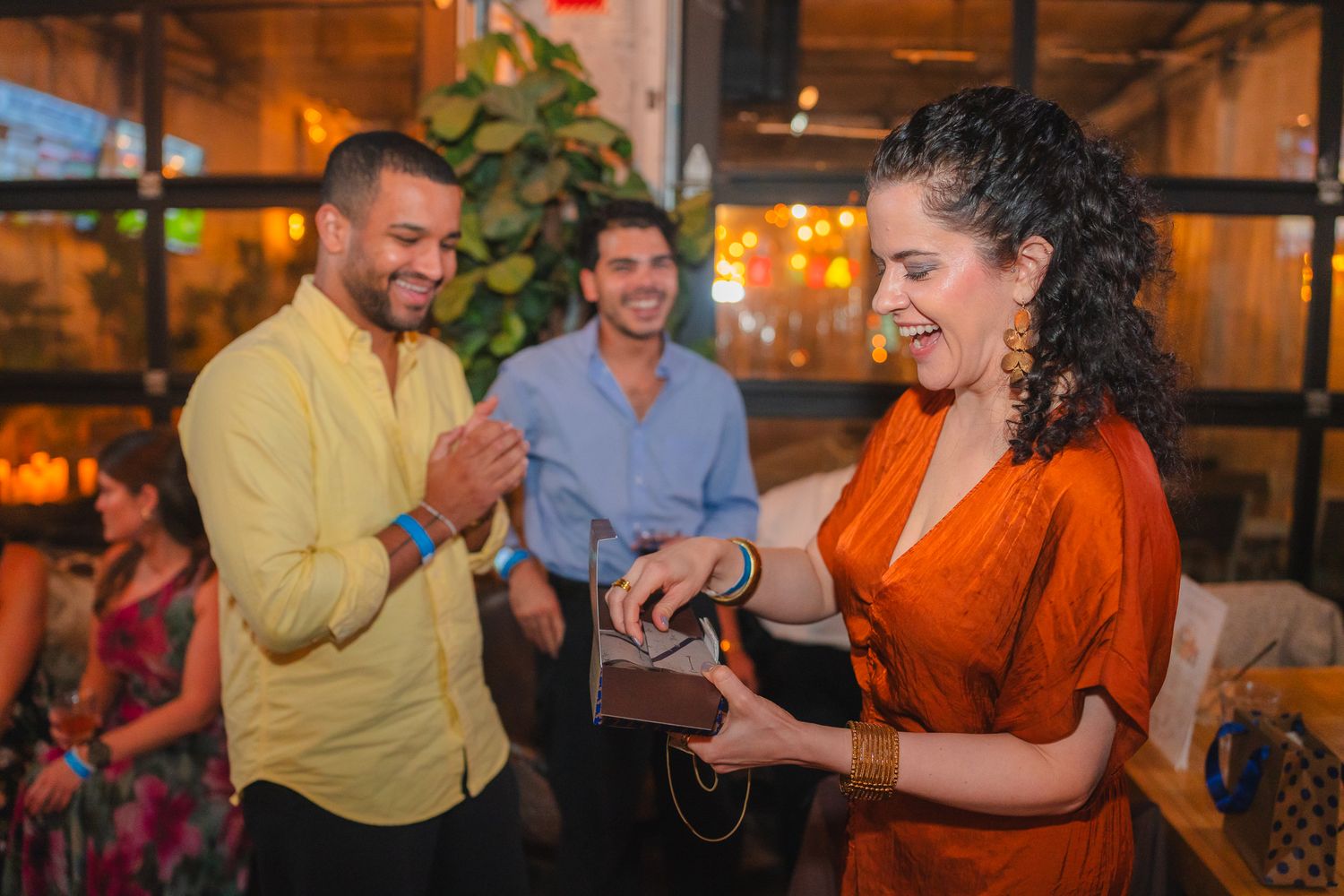 A group of people laughing and socializing together at a casual indoor gathering.