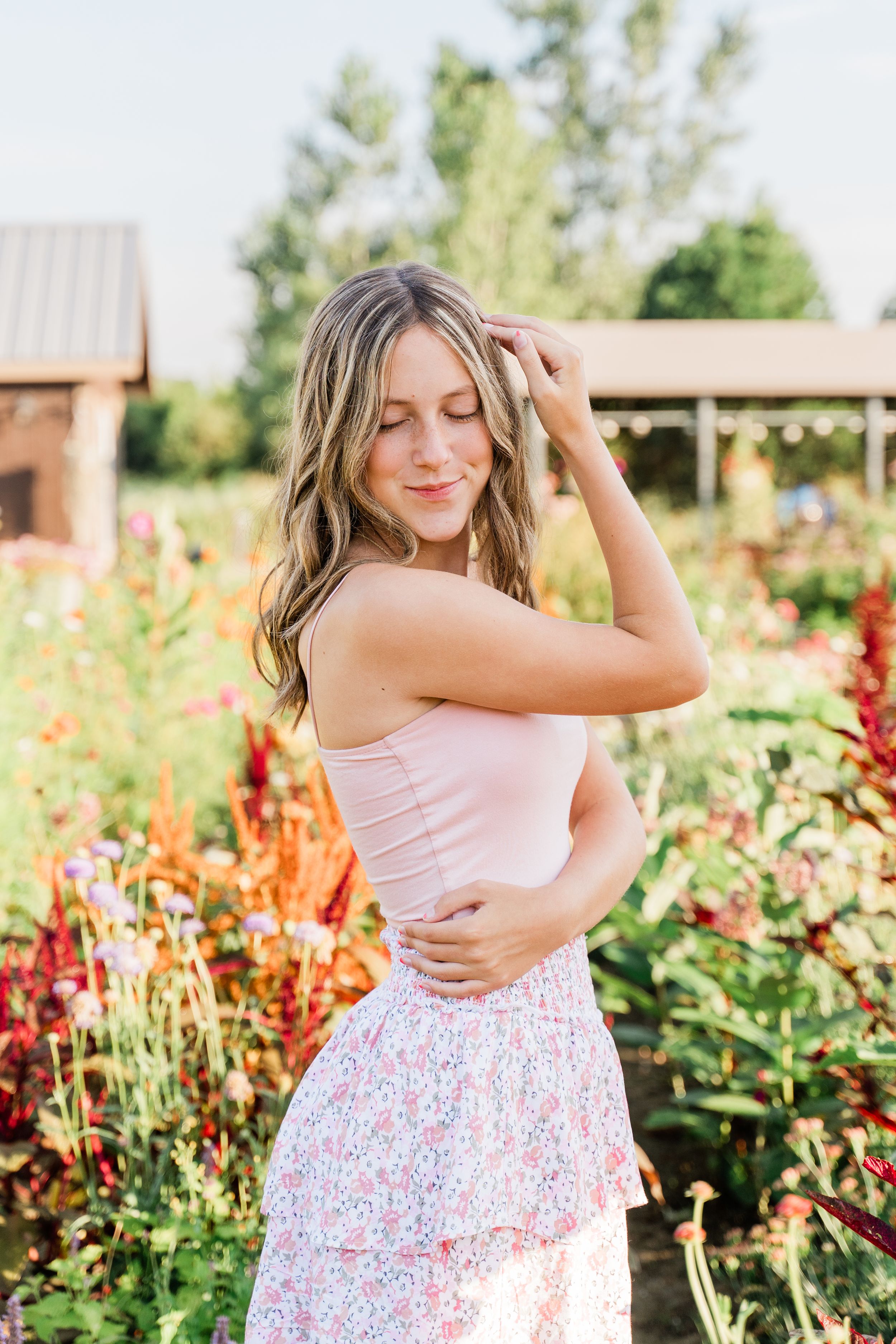 A series of photos showing someone in a pink top and floral skirt posing in a garden with vibrant red flowers.