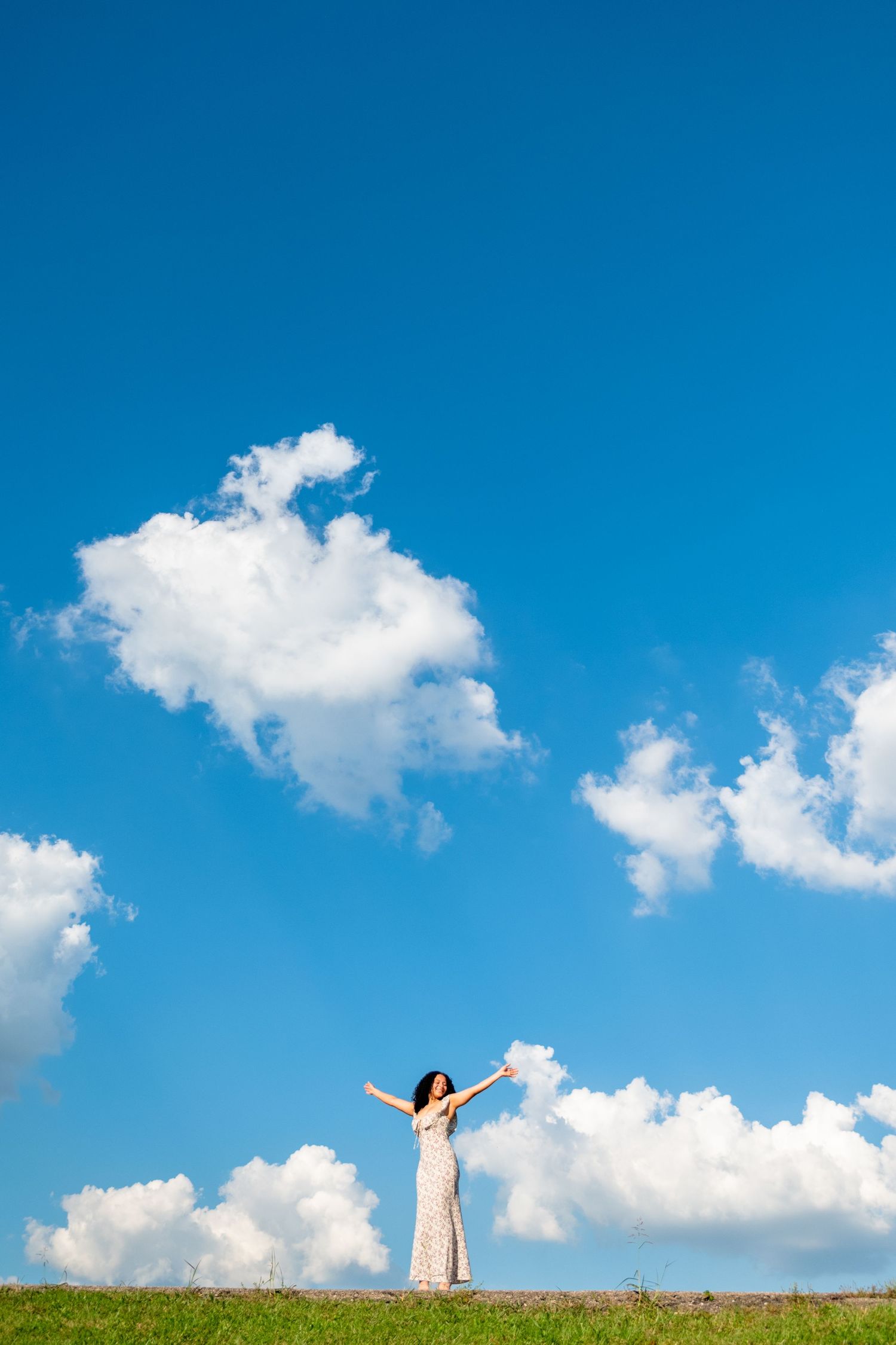 Dramatic panoramic series of a figure standing against a bright blue sky with white puffy clouds.