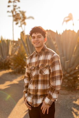 A casual portrait features a plaid shirt against agave plants in warm evening light.
