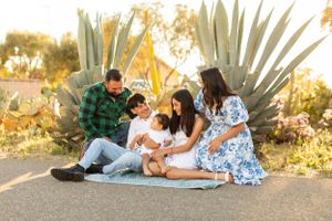 Family having picnic outdoors by large agave plants during golden hour sunset.
