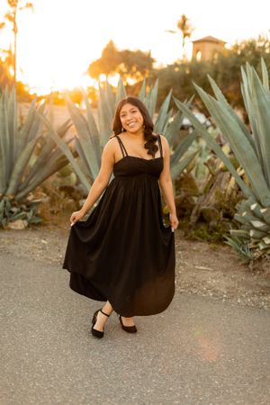 A black sundress is modeled against a backdrop of agave plants during golden hour sunset.