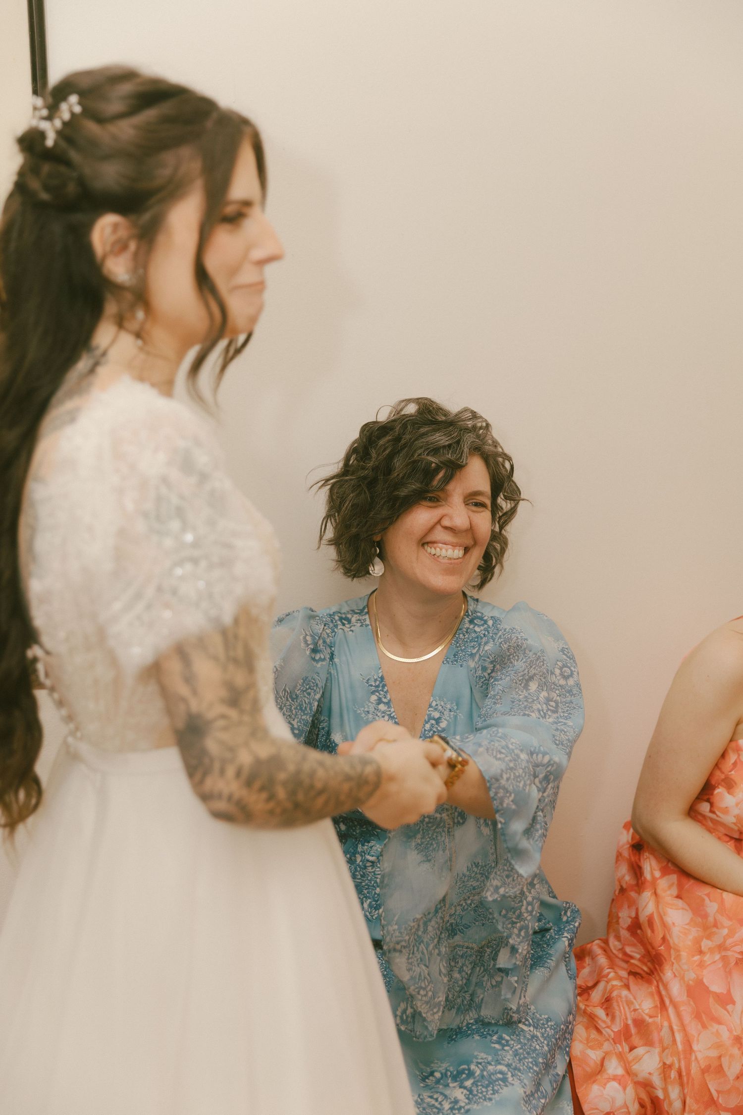 A joyful moment captured at a wedding celebration with people wearing a white lace dress and blue lace outfit.