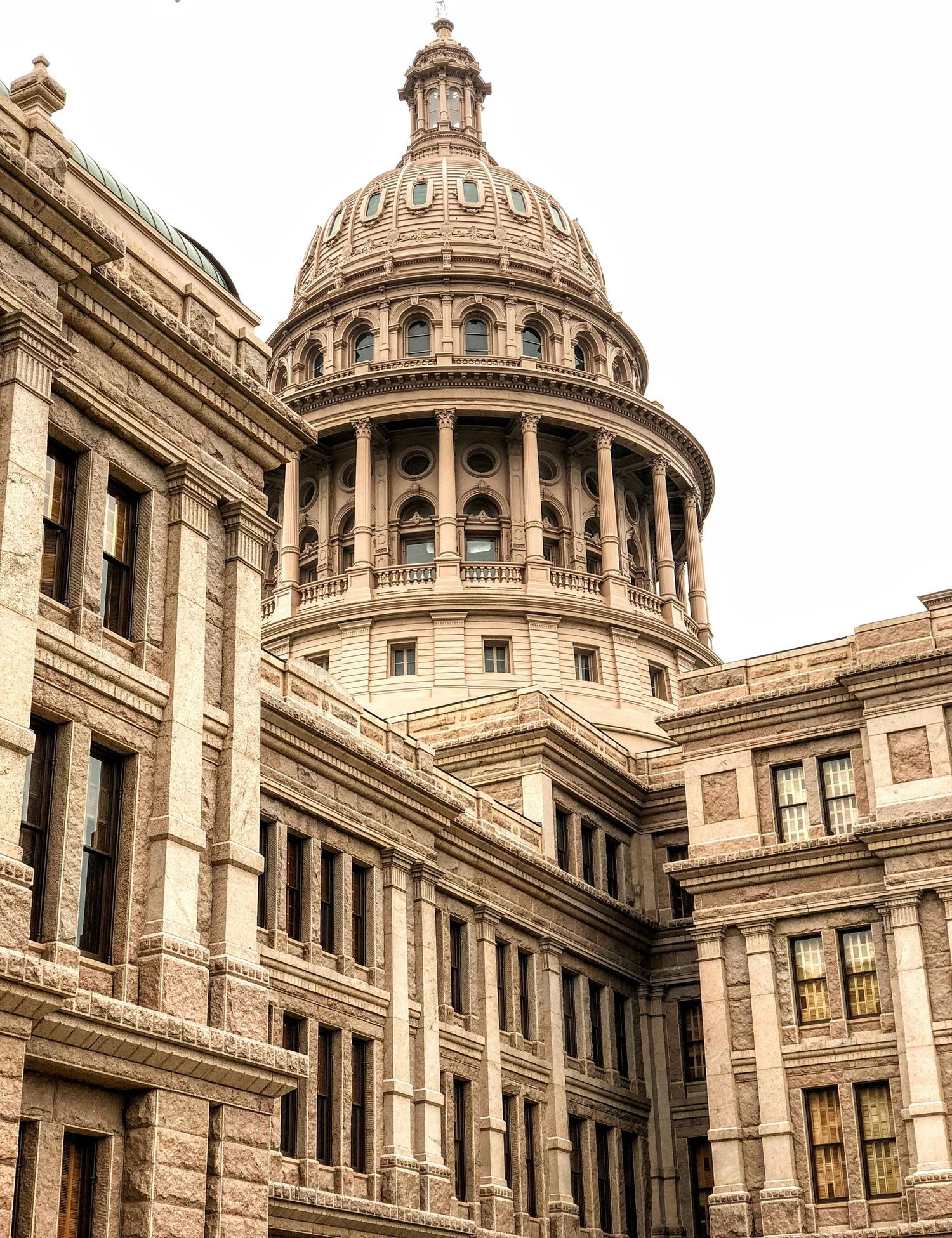 Architectural detail of the Texas State Capitol building dome and facade in Austin with ornate stone carvings.