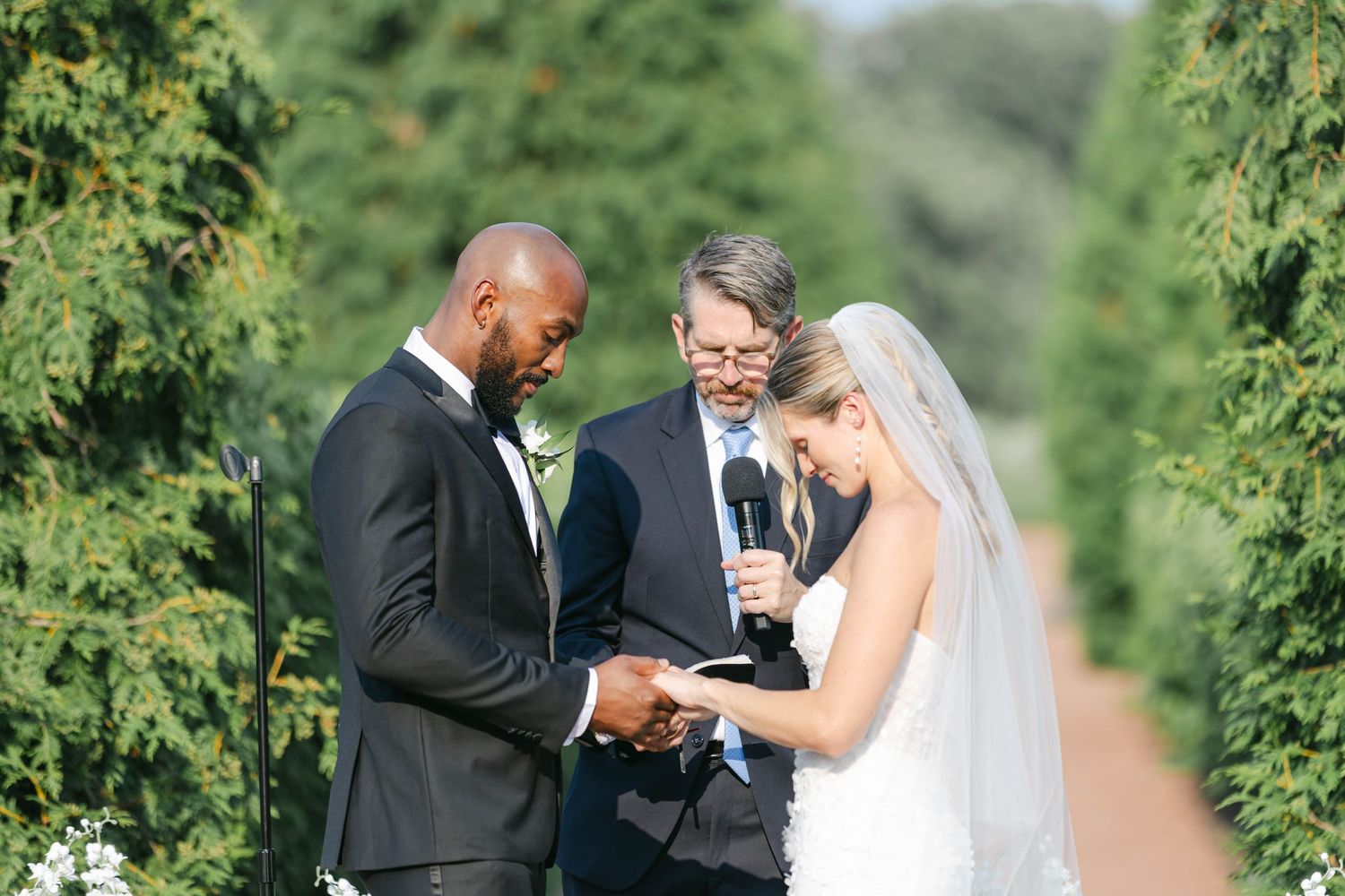 Couple shares tender moment in outdoor garden setting during wedding ceremony. - Elawa Farm