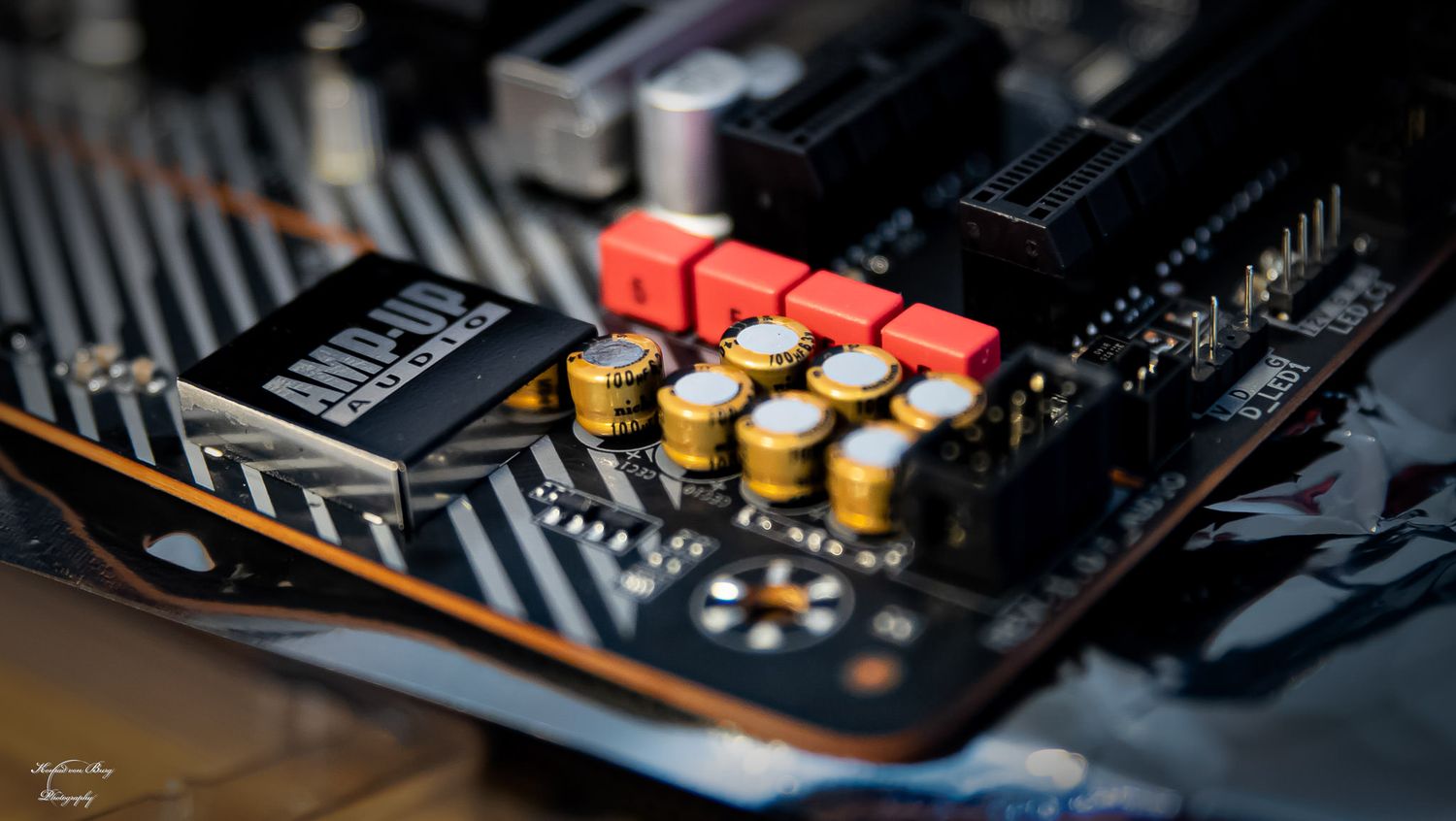 Close-up of electronic circuit board components with gold and red capacitors.