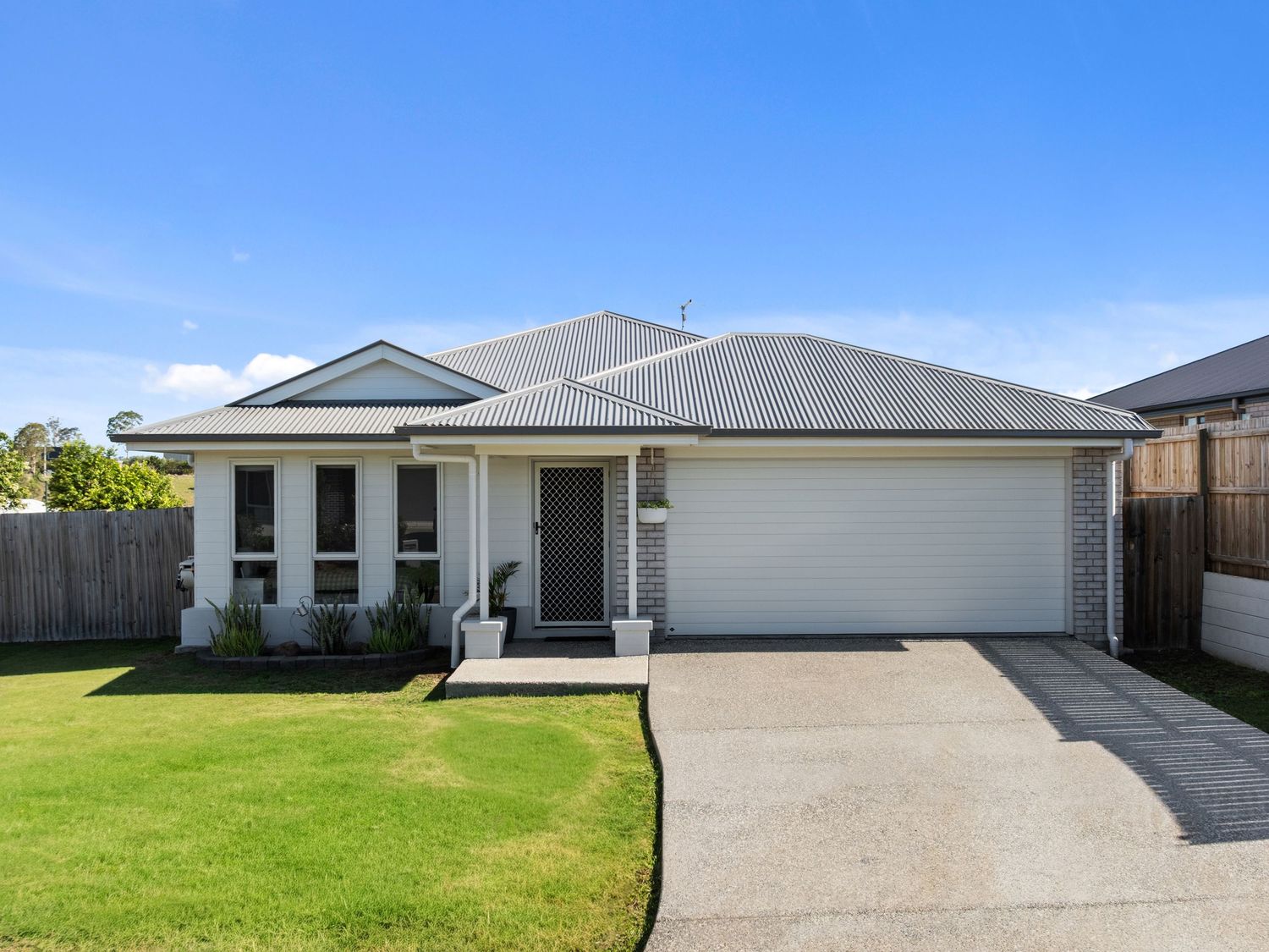 Row of contemporary single-story homes with white exteriors and manicured lawns.
