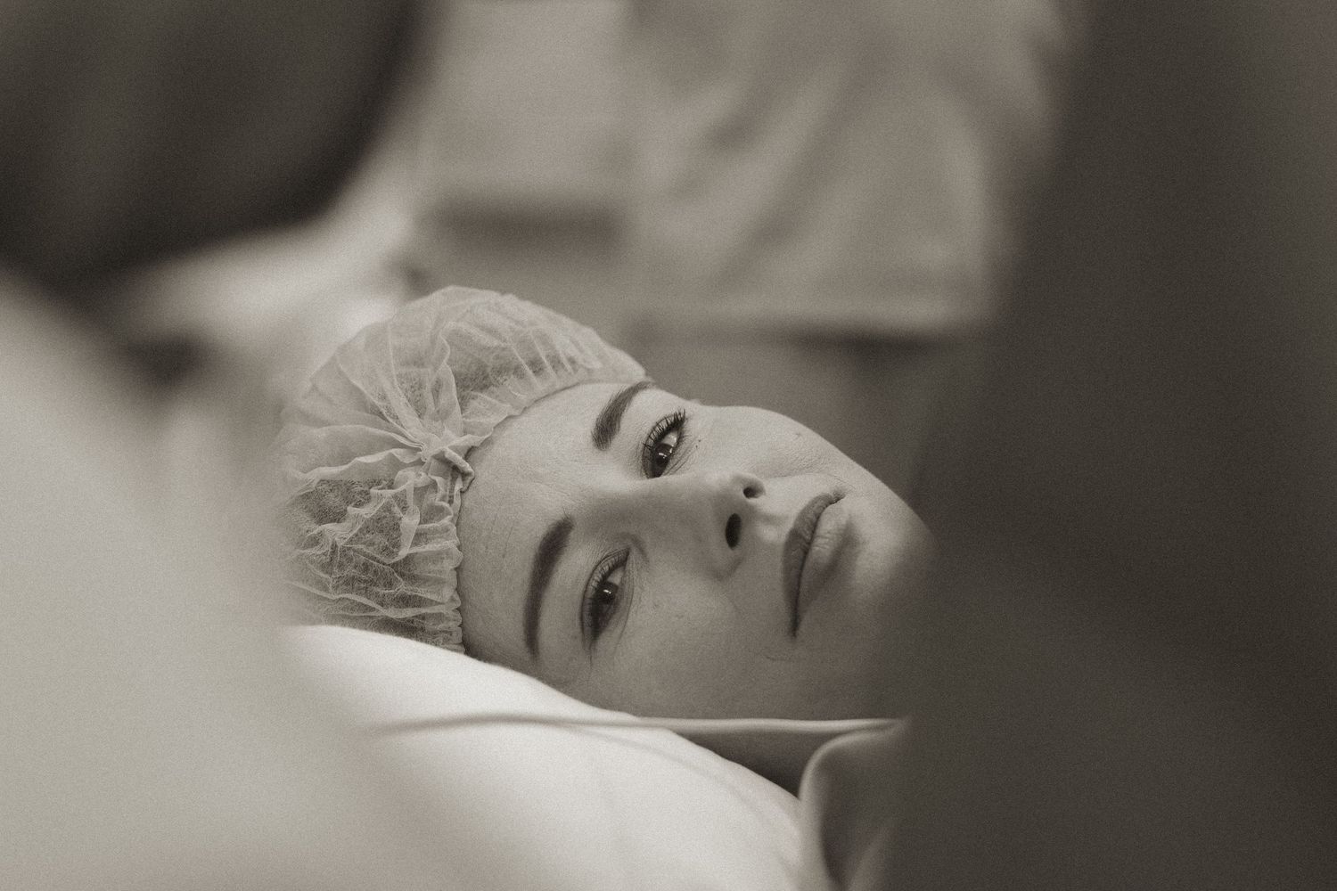 A black and white photo series shows a person lying down with a contemplative expression in different poses.