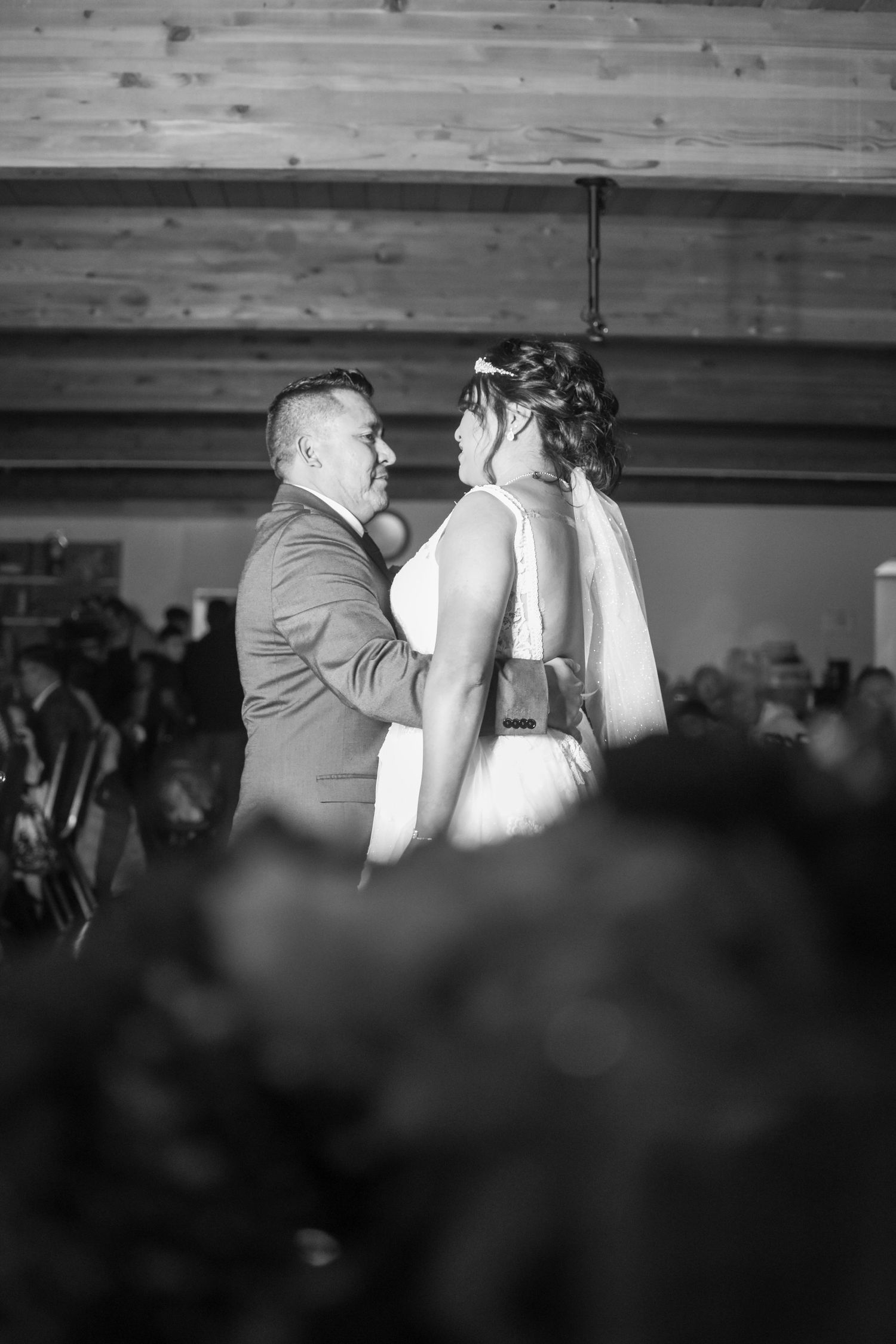 A tender moment captured in black and white during a wedding dance at an indoor reception venue.