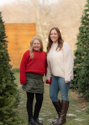 Winter photo session with red and cream outfits among evergreen trees.