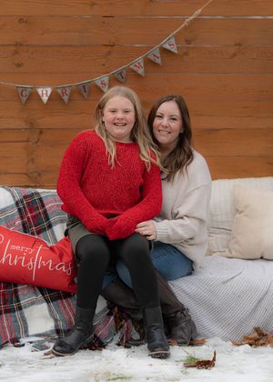 Christmas themed photo session with plaid blankets and festive pillows on wooden backdrop.