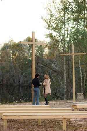 People work together to construct a wooden deck platform in a wooded outdoor setting during autumn.