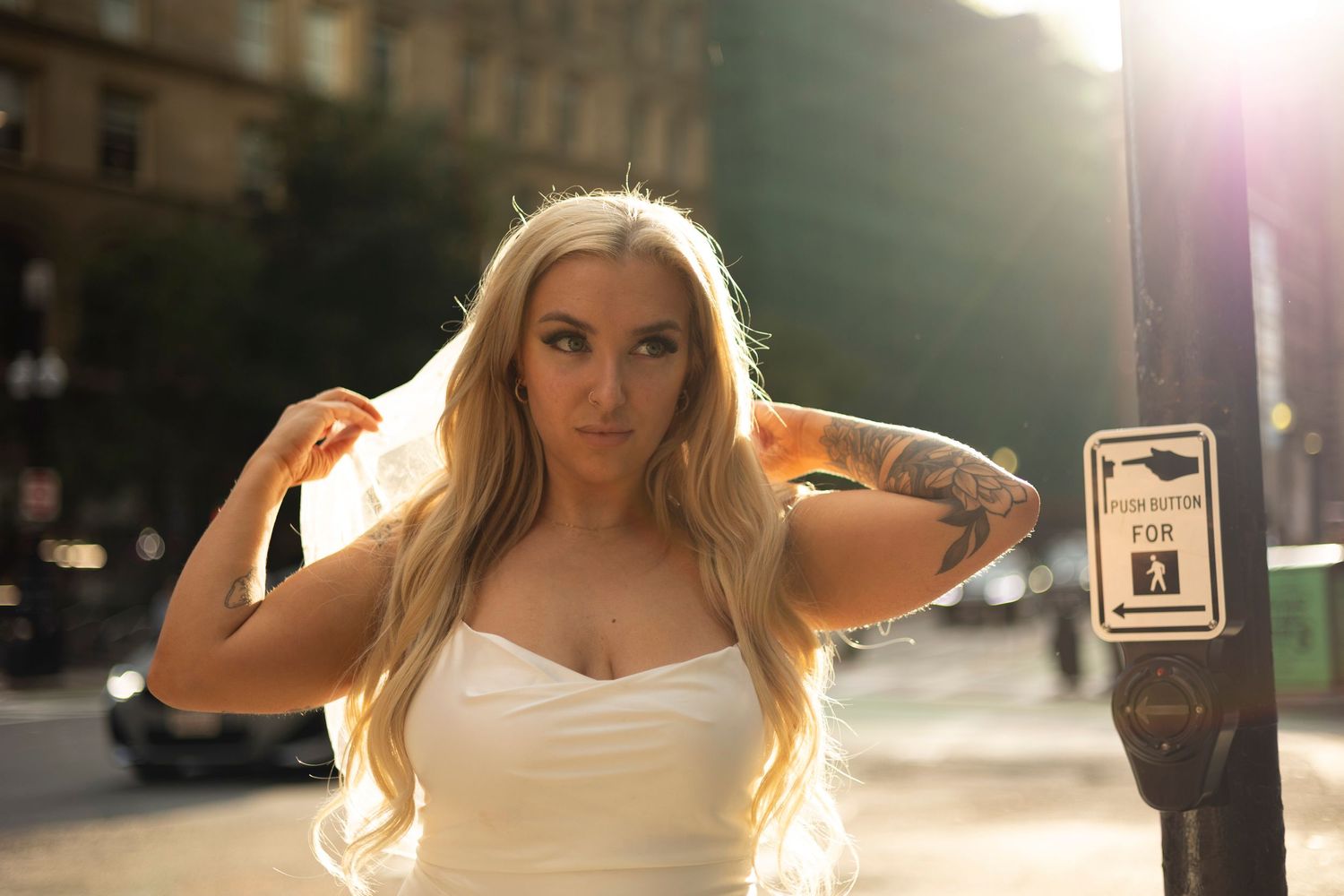 A person with long blonde hair poses outdoors in natural sunlight creating a dreamy backlit effect.