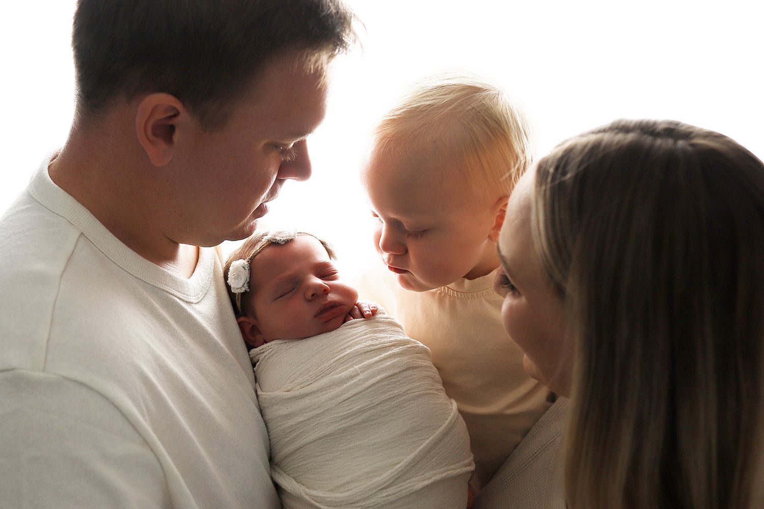 A series of intimate black and white photos showing tender moments between parents and their newborn baby.