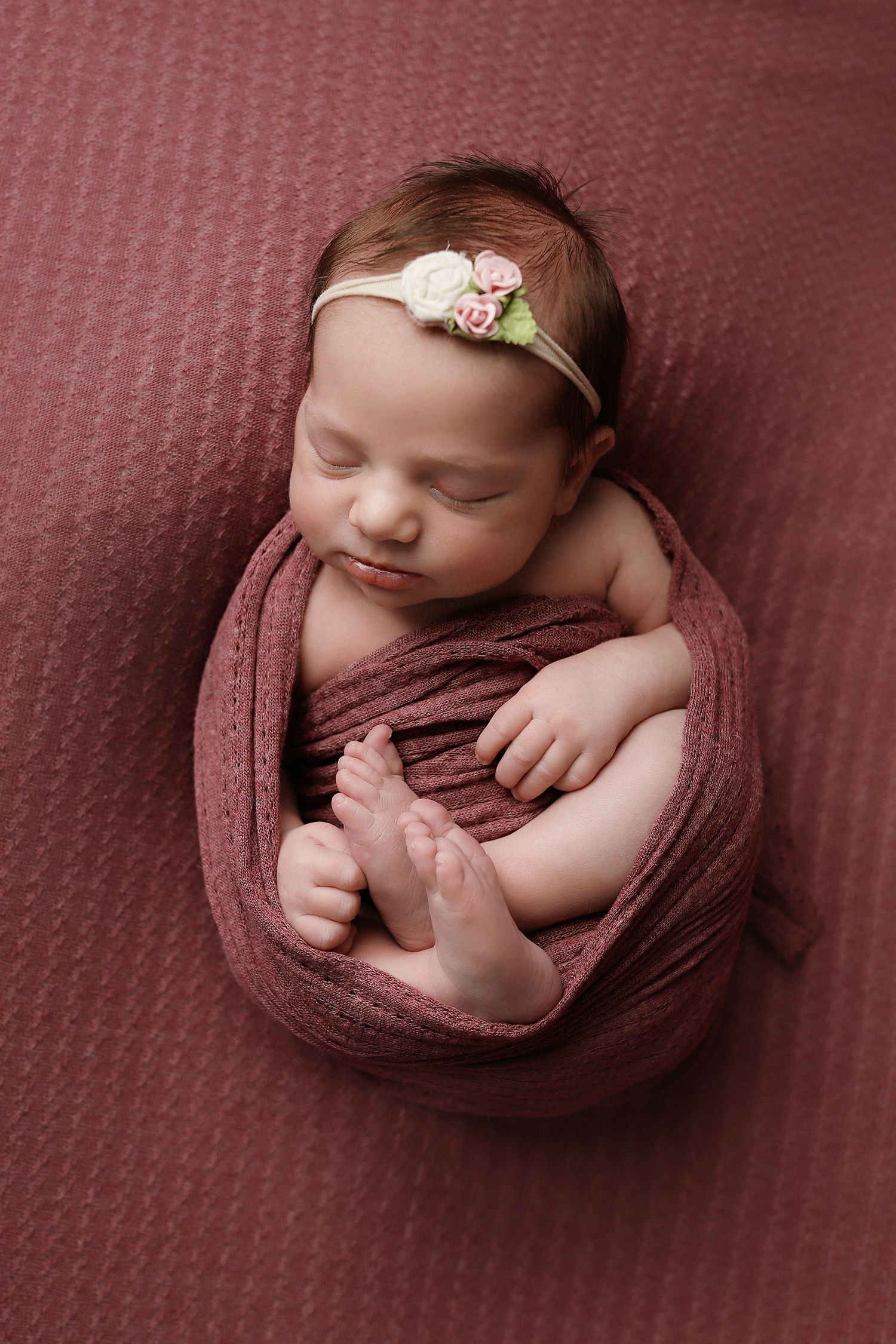 Sleeping newborn baby wrapped in soft mauve fabric shown in five artistic poses on matching textured backdrop.