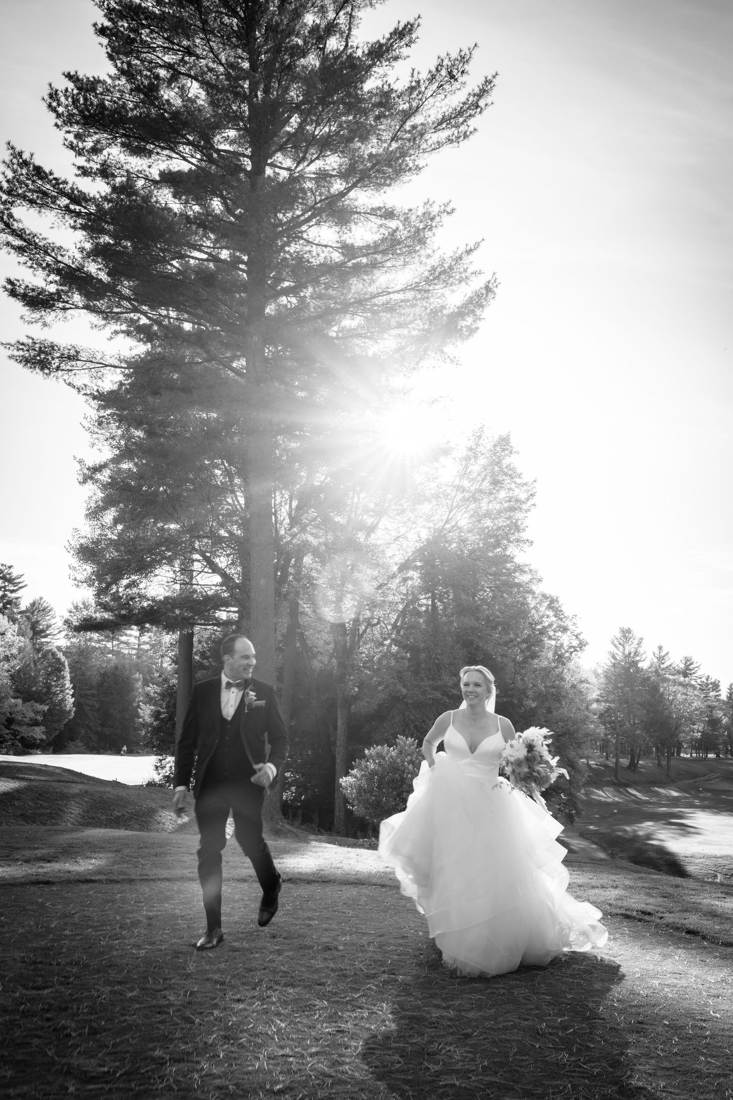 Photo de mariage noir et blanc de mariés marchant main dans la main sous les arbres à Estrie – photographe de mariage.
