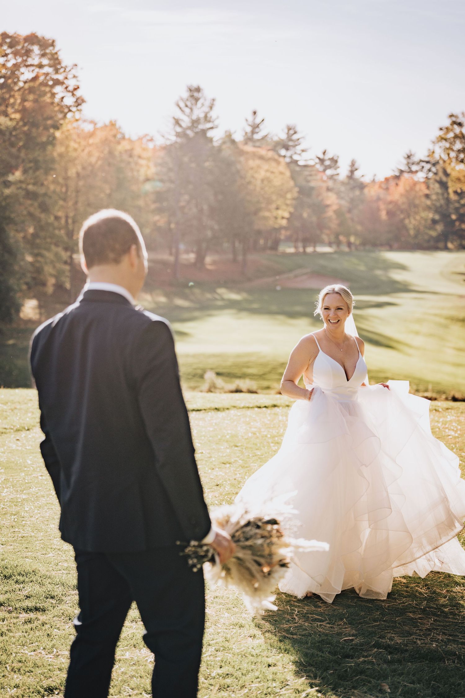 Mariée en robe princesse souriant au marié sur un terrain de golf automnal – photo de mariage élégante au soleil.