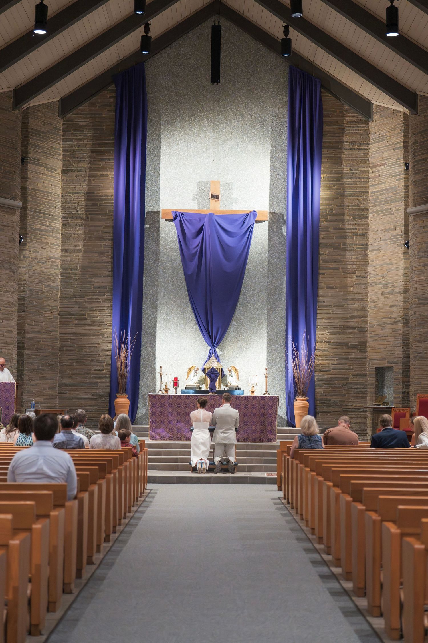 Interior of a modern church with wooden pews and purple drapes decorating the sanctuary space.