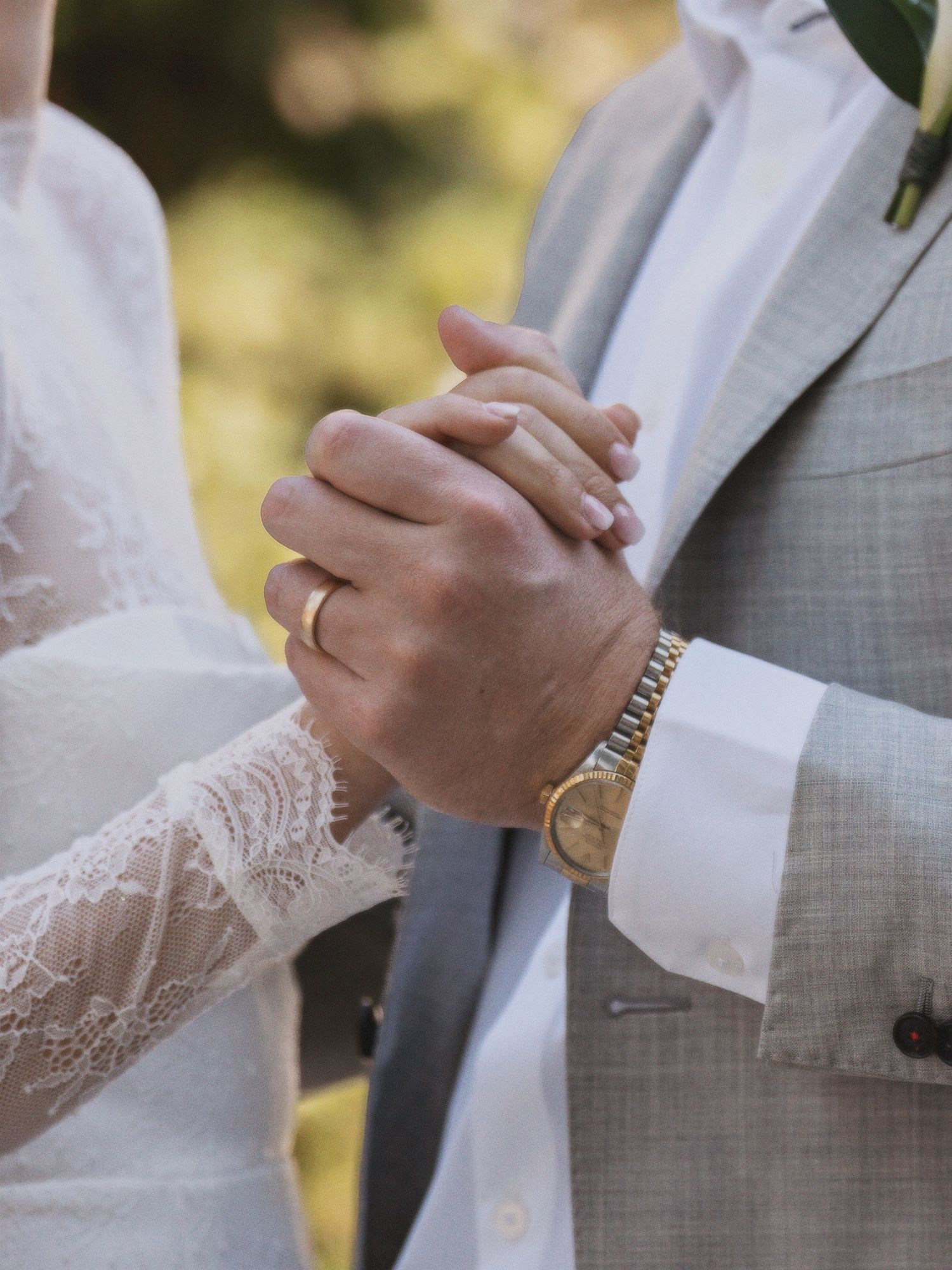 Close-up of lace sleeve details and hands during a formal ceremony.