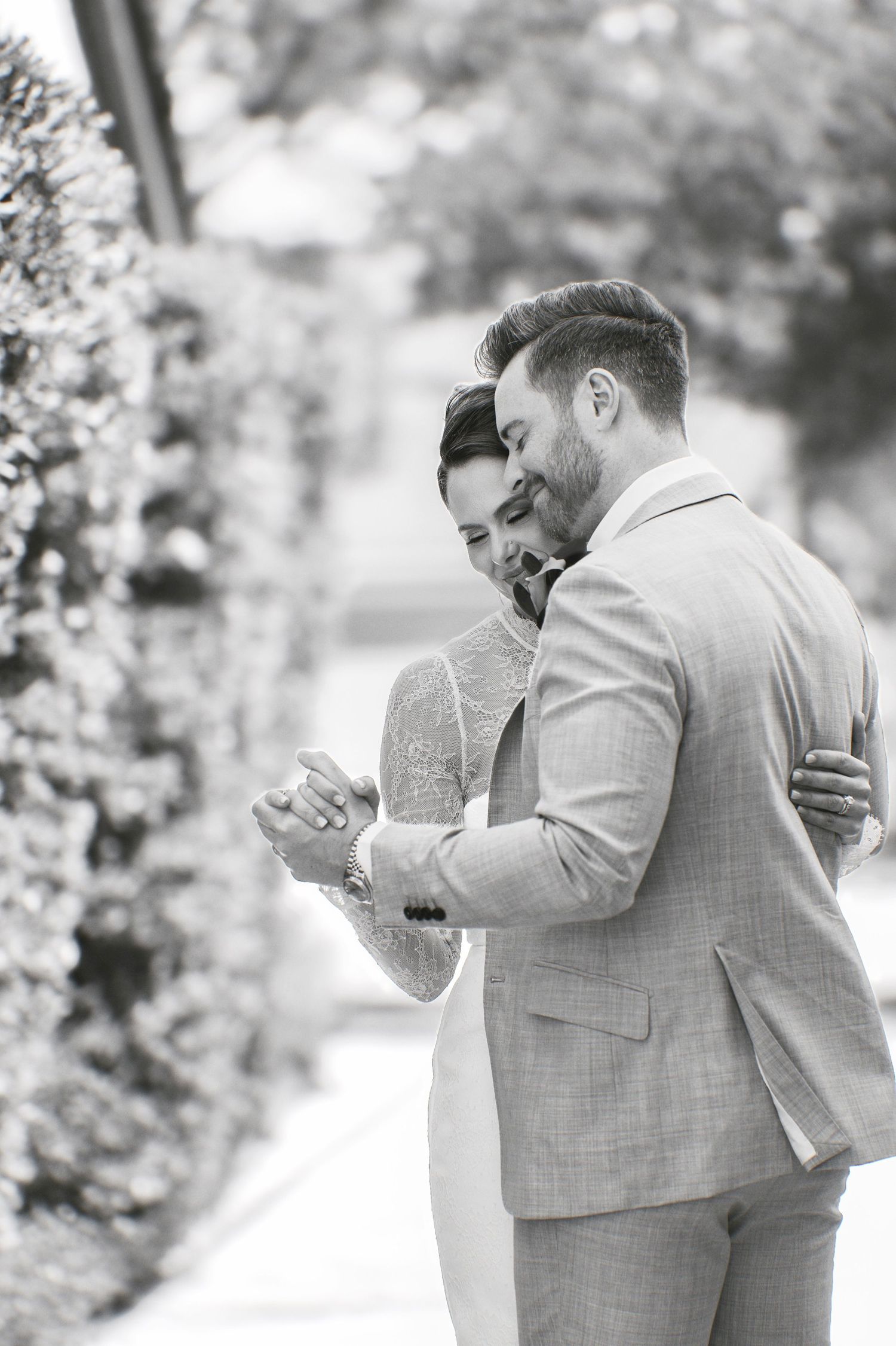 A couple shares an intimate moment outdoors surrounded by blooming trees and natural light.