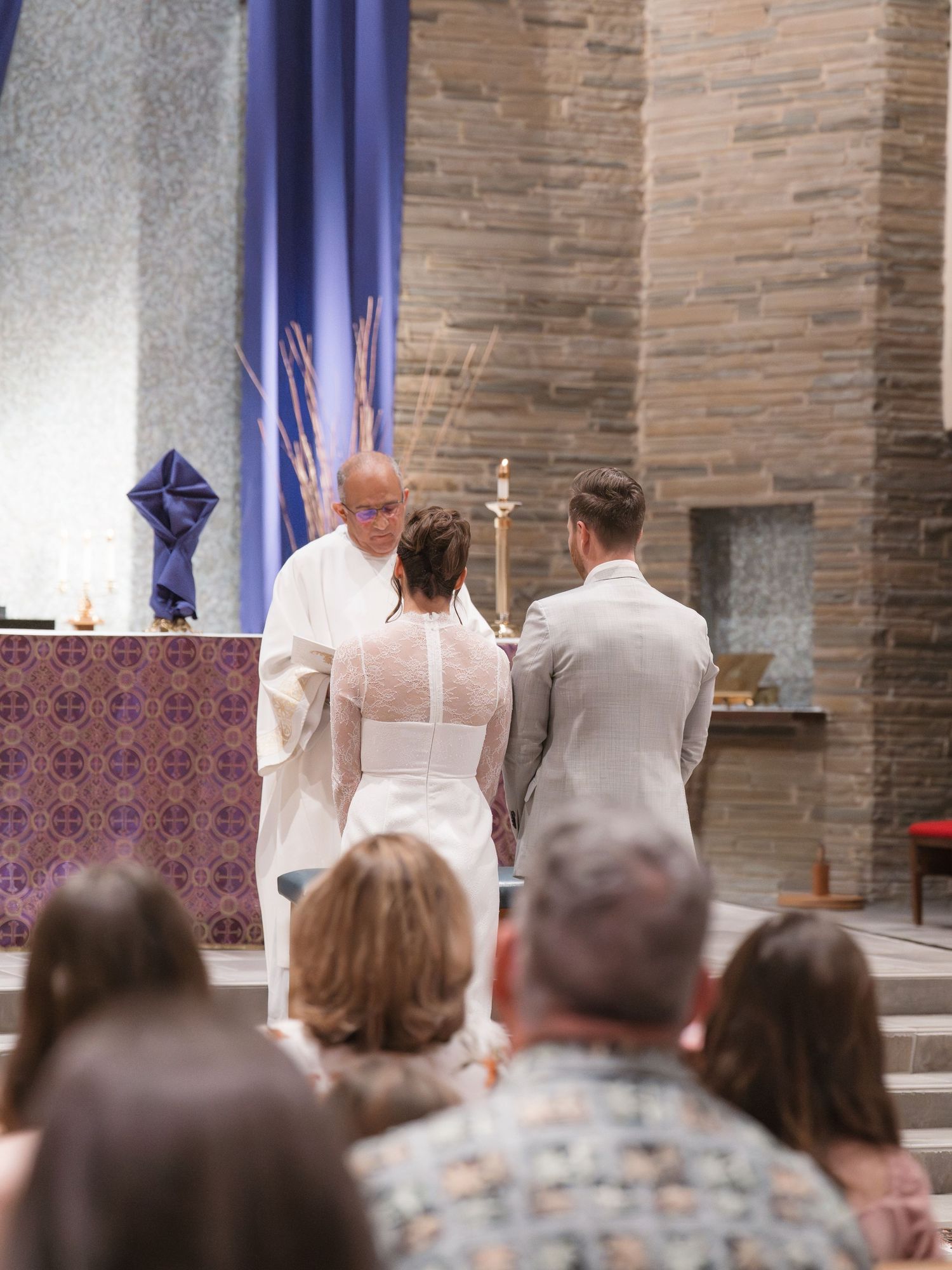 Church wedding ceremony with guests seated and purple decor accents.