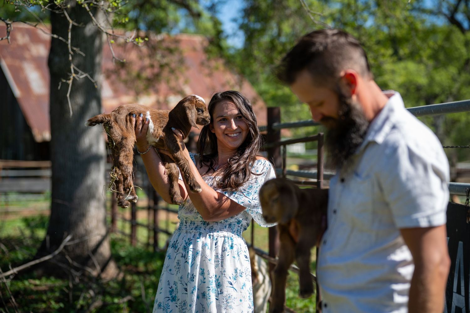 A couple enjoys a sunny day outdoors with their pet dog in a park setting.