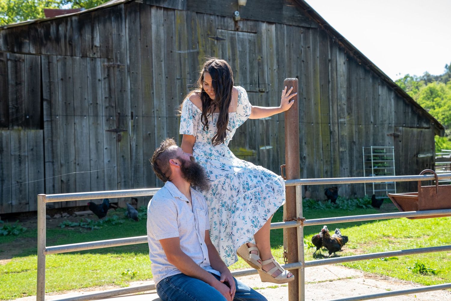 Couple sitting on rustic wooden porch steps of a weathered barn on a sunny summer day.