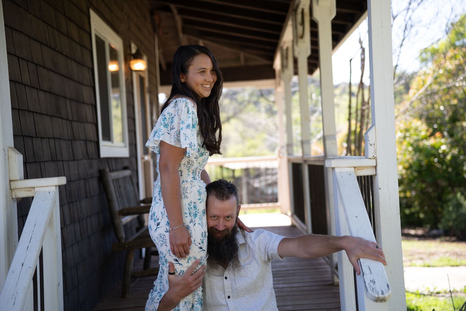 A couple shares a joyful moment with guests on a rustic wooden porch during a celebration.