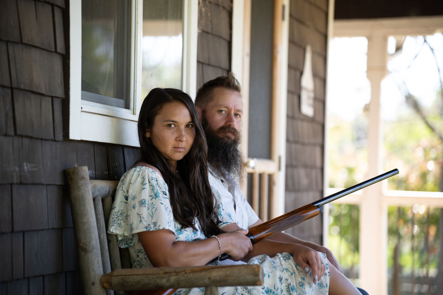 Two people sit on a porch swing while reading books together on a sunny afternoon.