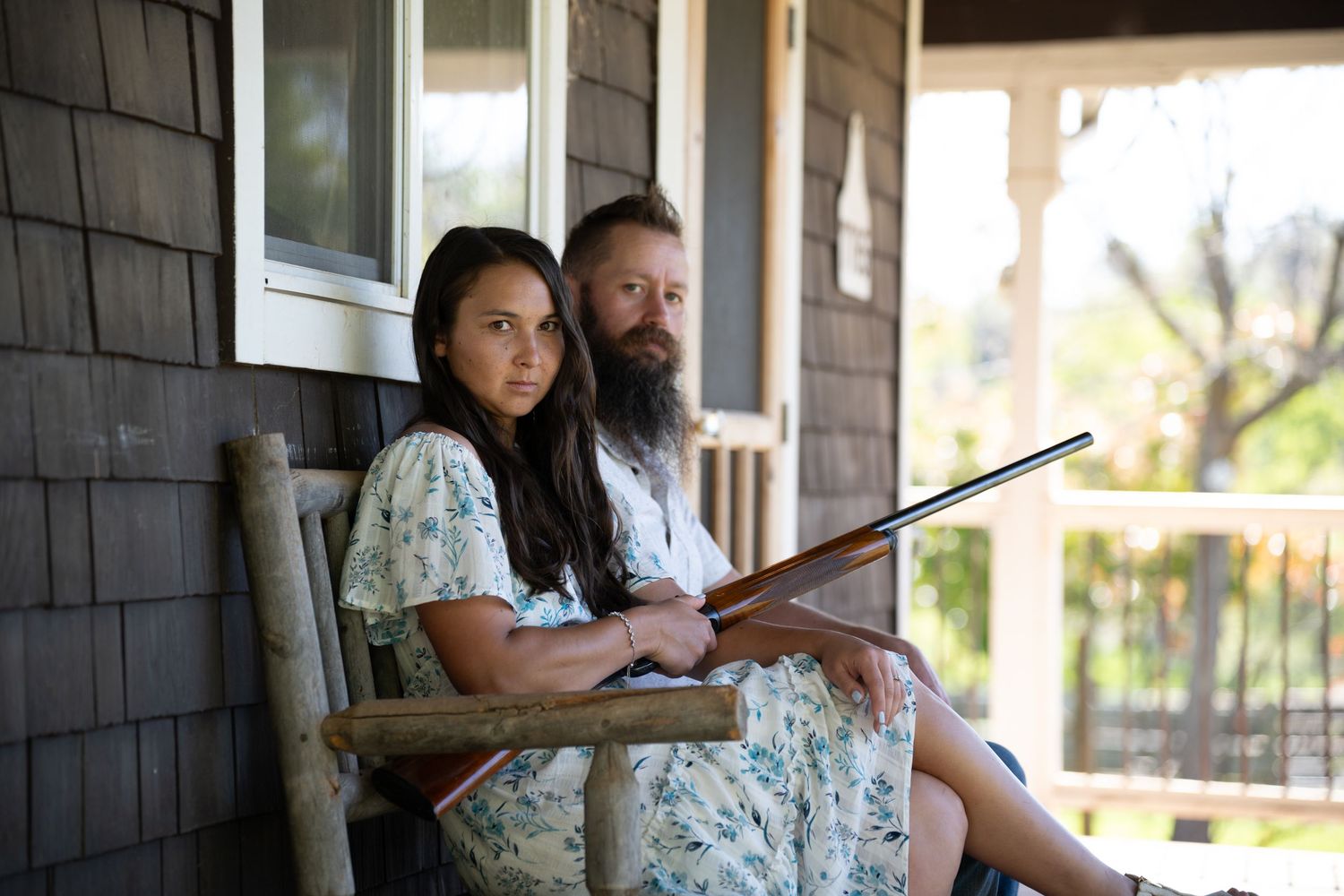 Two people sit together on a porch swing while reading a book in the afternoon light.