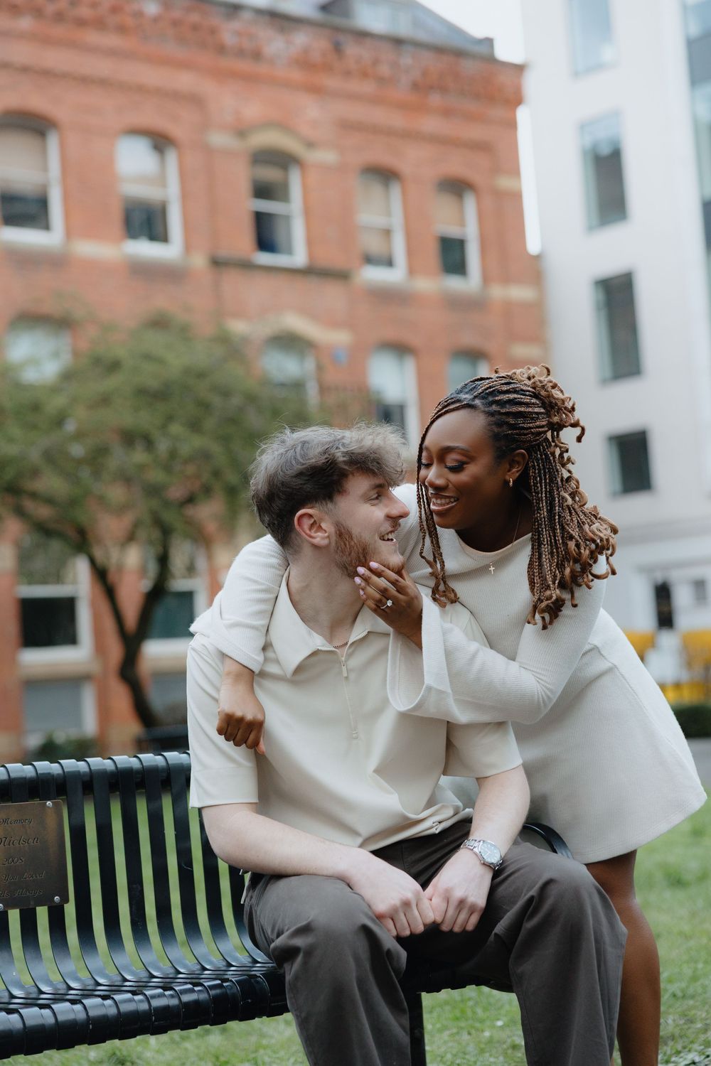 Two people in white shirts share a candid moment while sitting together on a park bench.