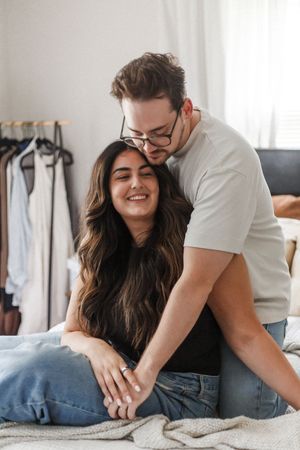 Candid moments of relaxation and laughter shared between a couple and their pet dog on a comfortable sofa.
