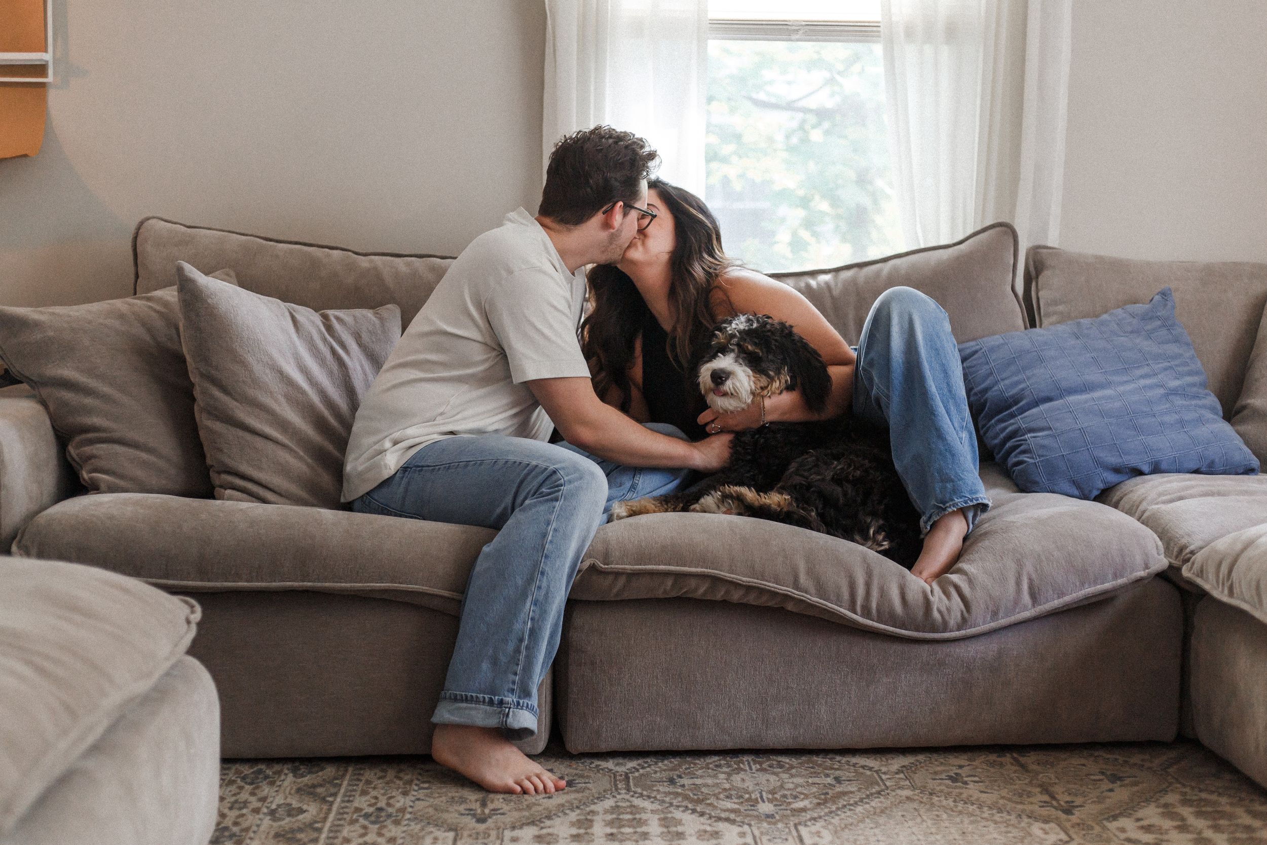 Casual lifestyle photos showing tender moments between a couple and their pet dog on a comfortable sofa.