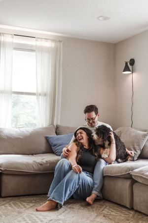 Family members relax and cuddle together on a comfortable gray sectional sofa in a bright living room.