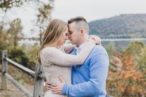 A couple shares romantic moments in an autumn mountain setting with colorful fall foliage in the background.