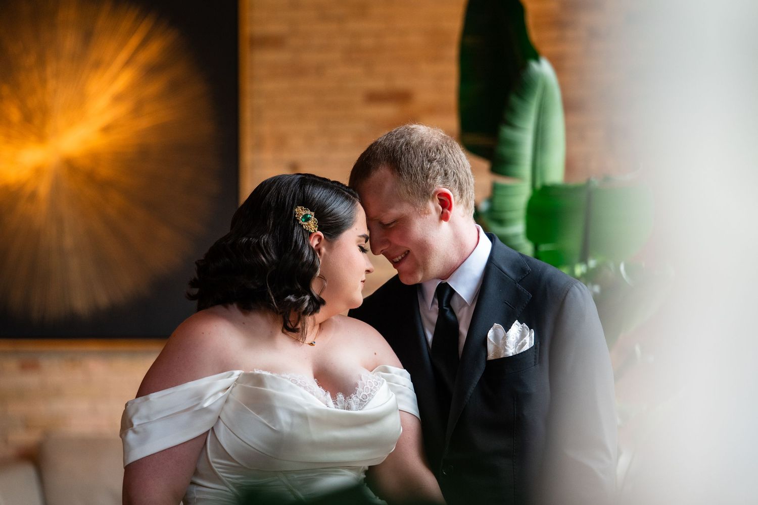 Bride and groom share an intimate moment, smiling at each other in elegant wedding attire at a stylish indoor venue.