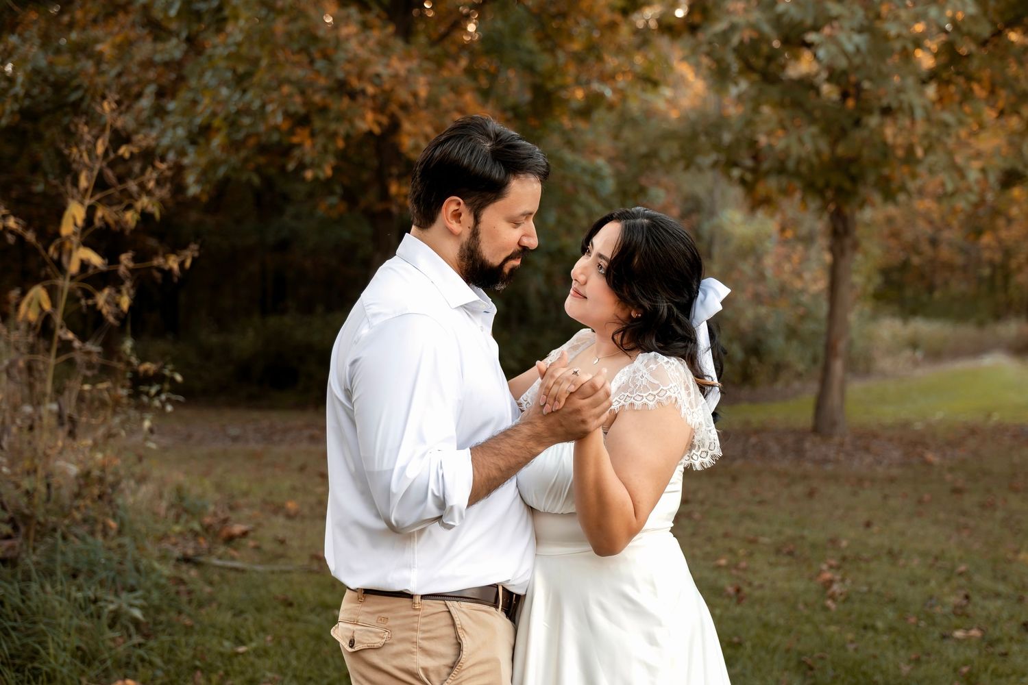 A couple shares a romantic dance outdoors surrounded by colorful autumn foliage.
