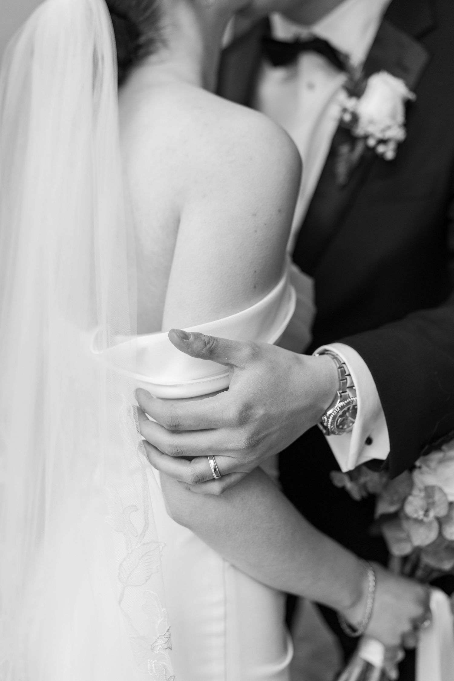 A couple shares an intimate moment on a curved staircase with warm wood accents and modern architecture.