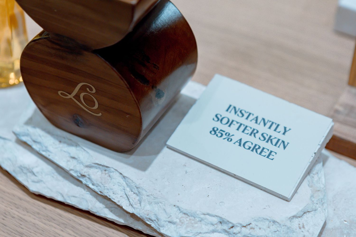 Wooden stamp beside a card reading Instantly Softer Skin 85% Agree on a marble surface.
