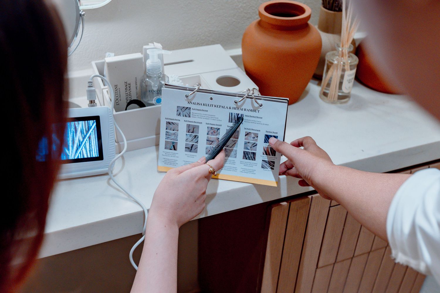 Two people reviewing a beauty treatment brochure with before and after photos at a modern salon desk.