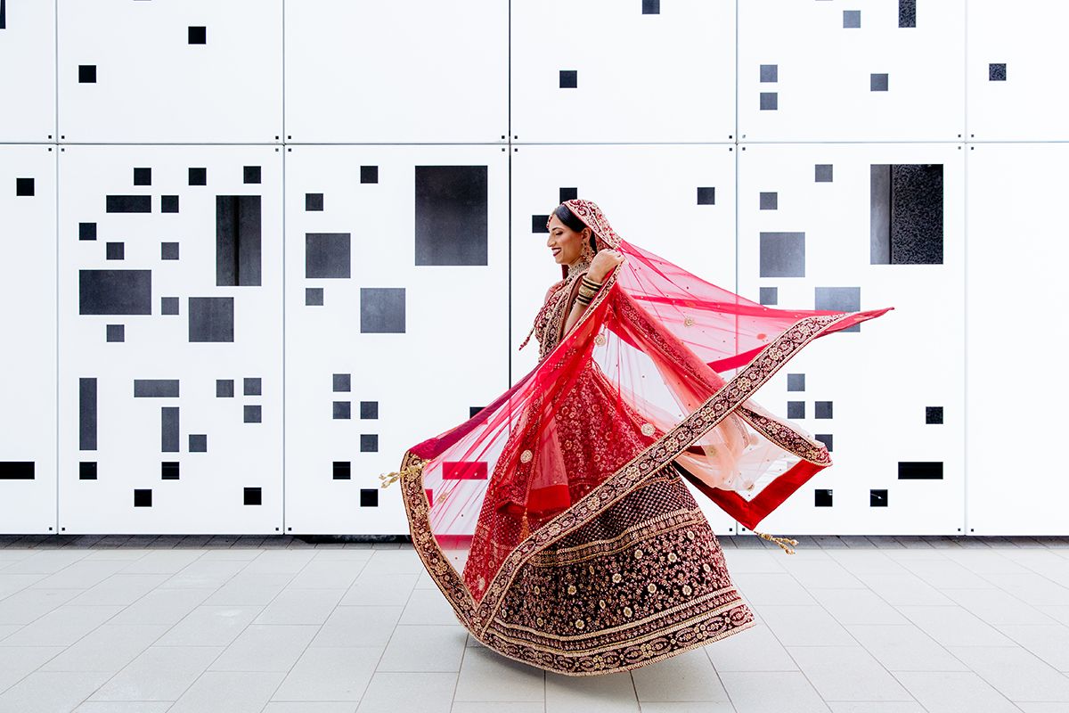 Auckland wedding photographer capturing a bride spinning in a red lehenga with veil flowing