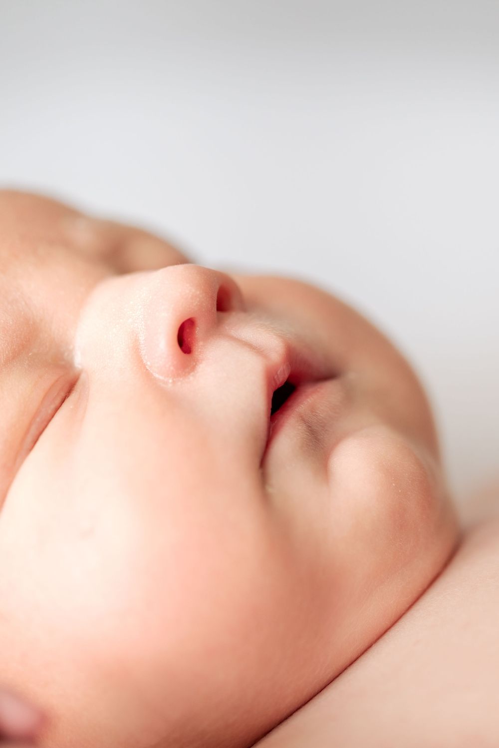 Close-up of a peaceful sleeping newborn baby's face with soft skin and tiny features.