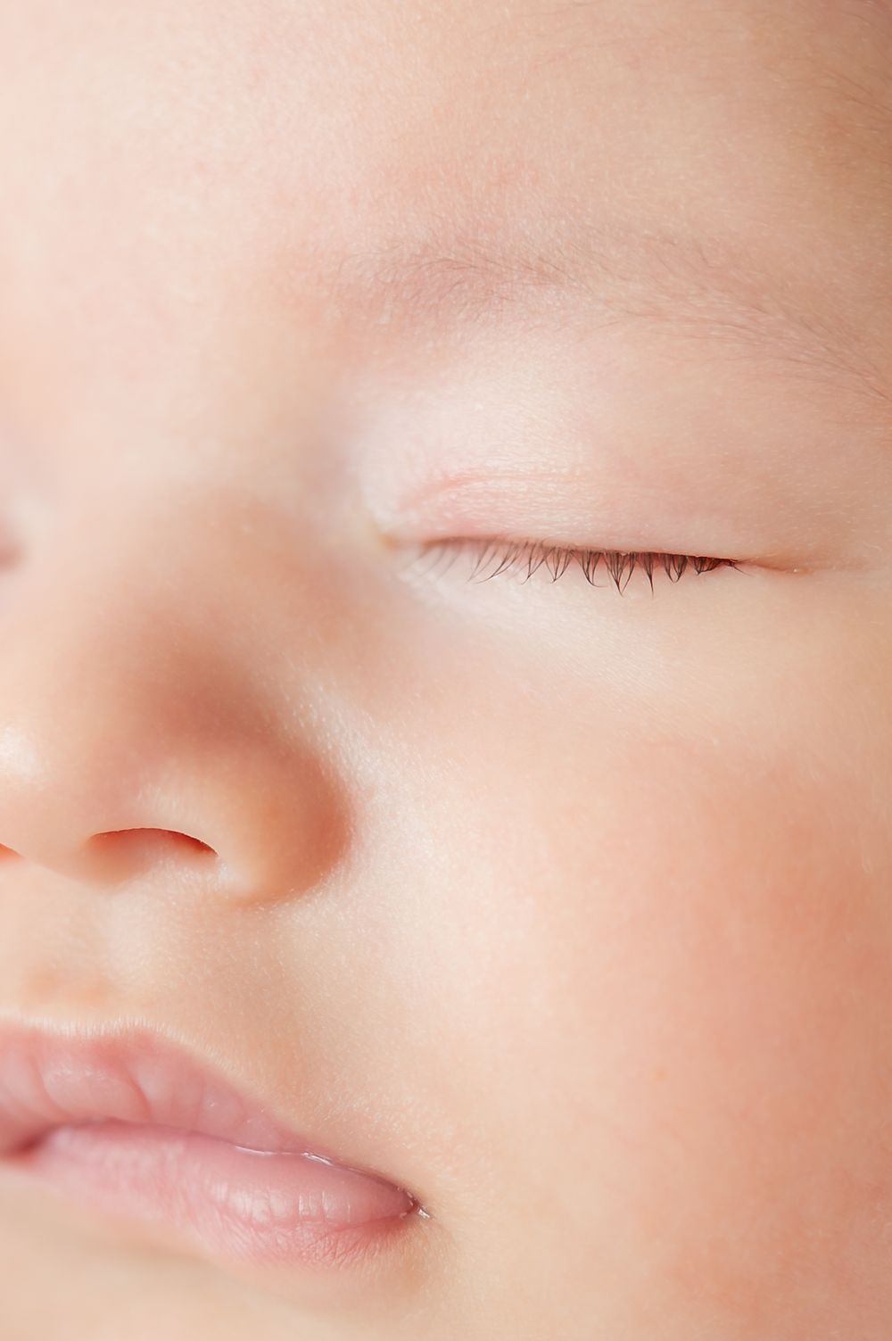 Close-up portrait of a peaceful sleeping newborn baby with soft skin and delicate eyelashes.