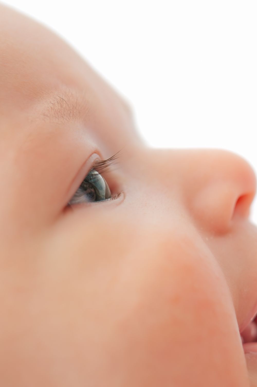 Close-up portrait of a baby's face with bright blue-green eyes and soft skin looking upward.