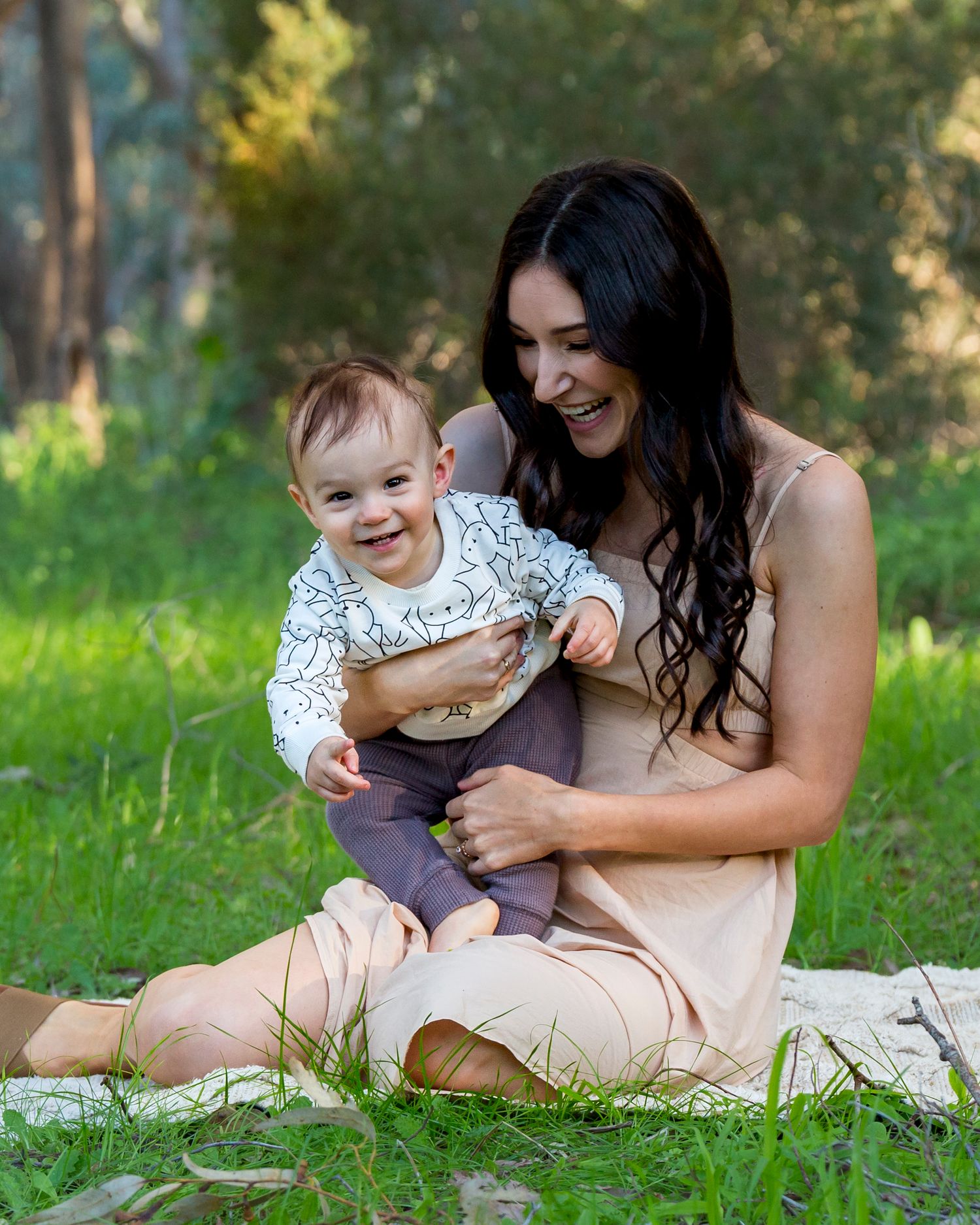 Unposed, joyful photo of mum and son sharing a laugh on a mat during a relaxed family session