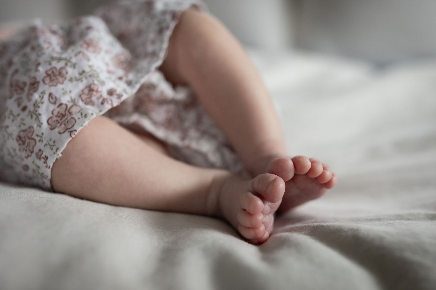 Close-up of a newborn babys tiny feet resting on a soft white blanket.