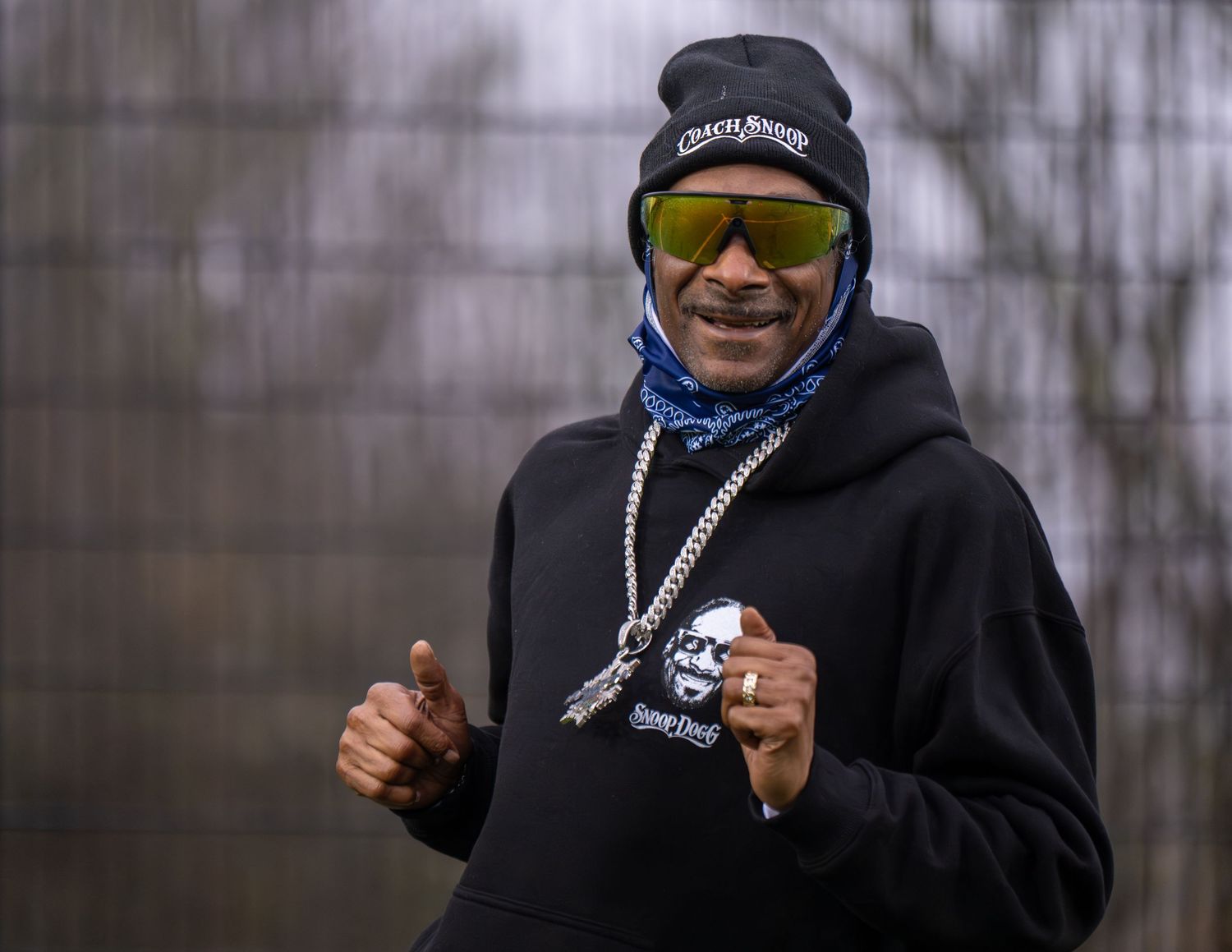 Person in black hoodie and sunglasses holds up scissors against dark background in multiple poses.