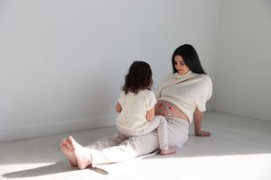 A series of minimalist photographs showing a person in white clothing sitting against a white wall in different poses.